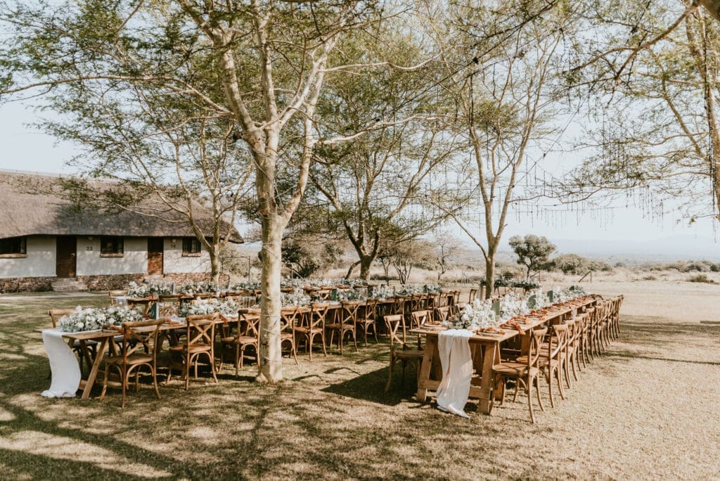 Safari wedding reception with tables set up beneath acacia trees