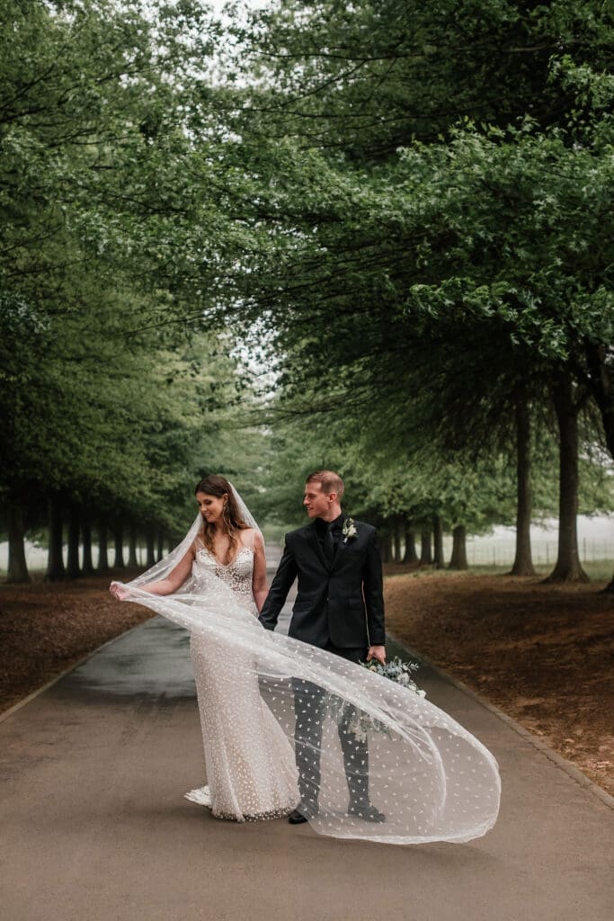 Bride and groom walking down main road. Bride has flowing veil.