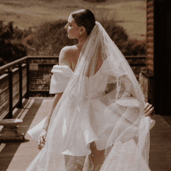 Bride wearing short dress with off the shoulder sleeves and long veil