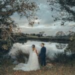 Bride and groom holding hands and looking out over pretty dam