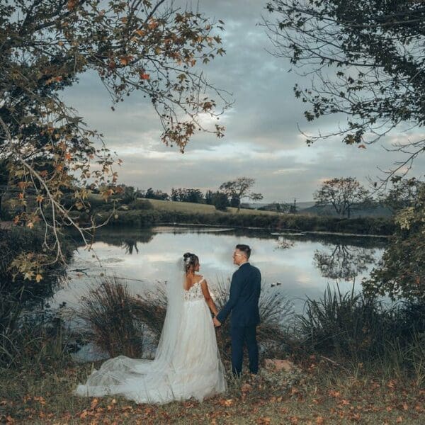 Bride and groom holding hands and looking out over pretty dam