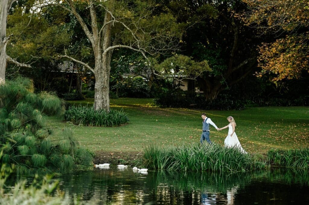 Bridal couple walking hand in hand next to dam