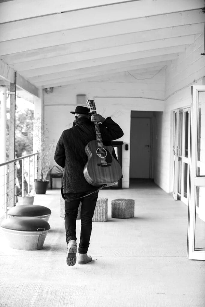 Man walking with guitar strapped toback