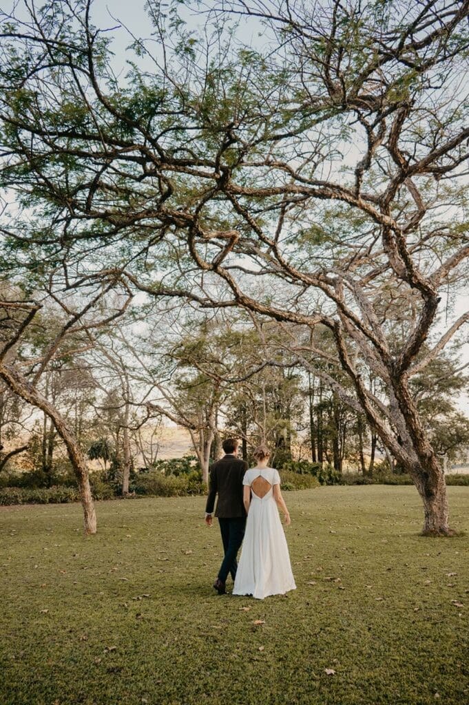 Bride and groom taking a romantic stroll in grassy garden at Eden Lassie