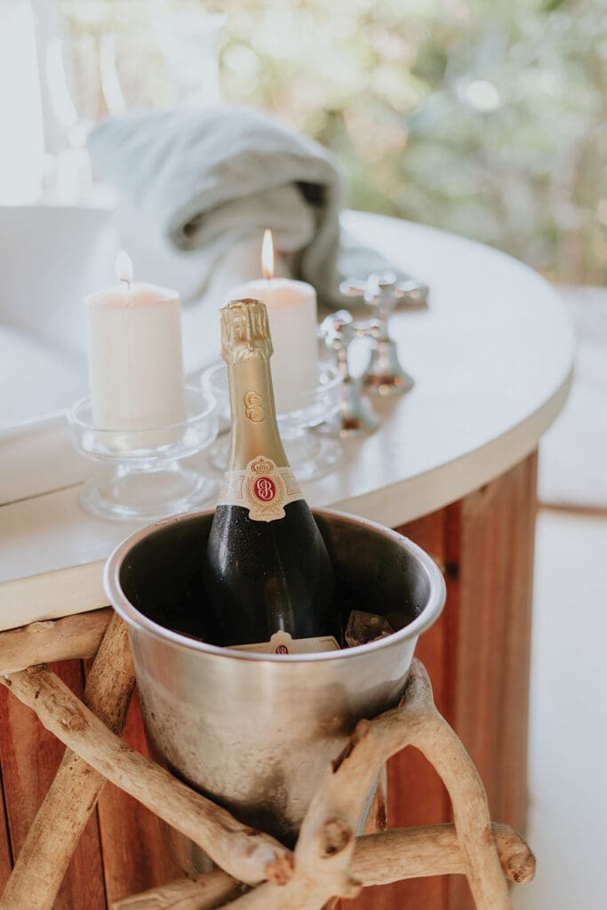 Champagne bottle in ice bucket next to spa bath