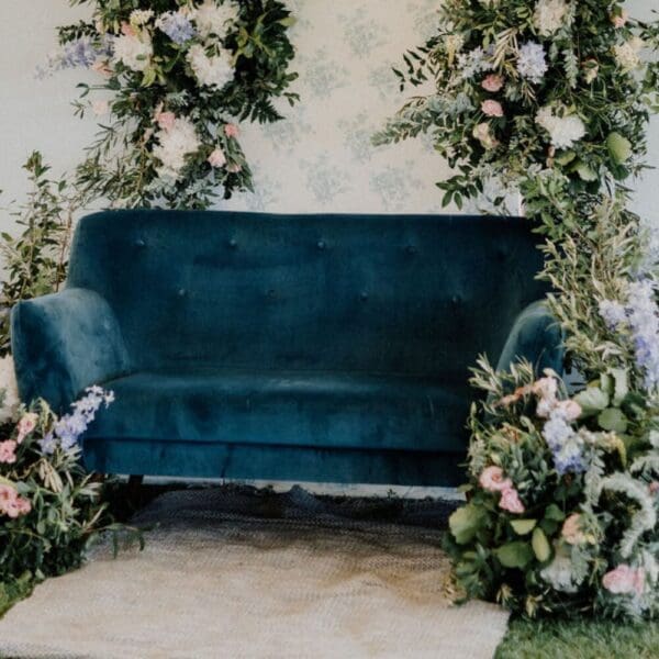 Blue velvet couch surrounded by flowers and candles