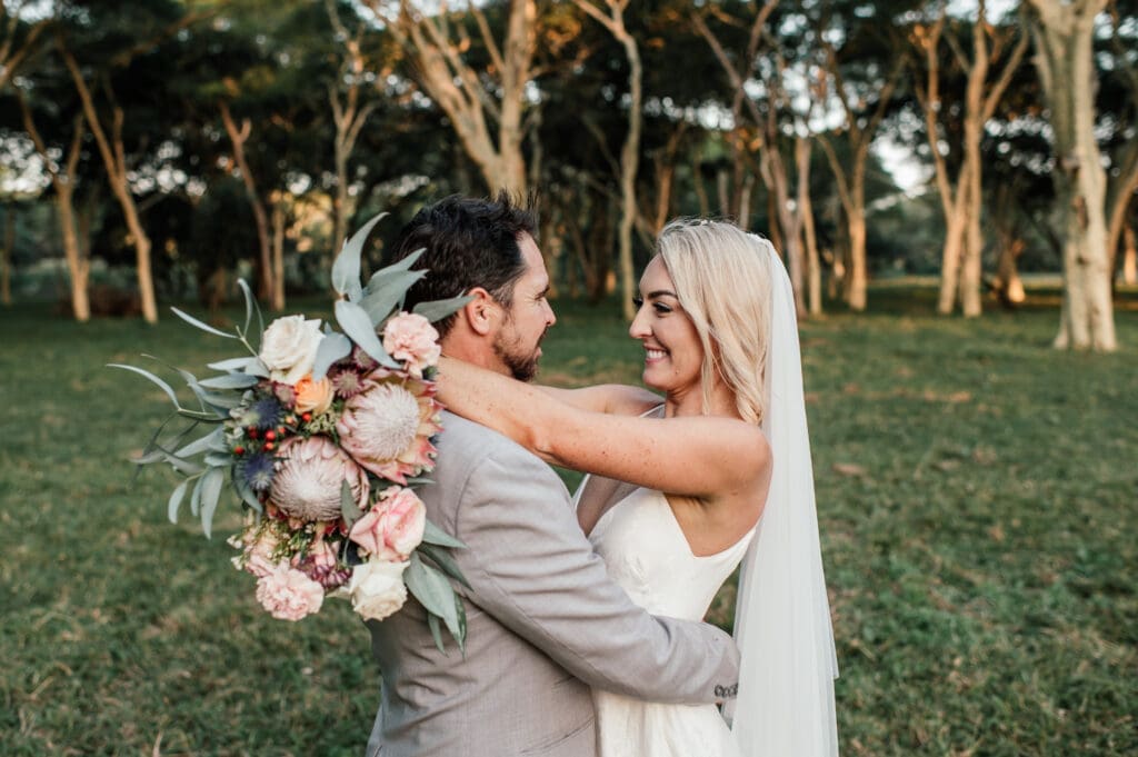 Bride with arms around groom's neck holding bouquet