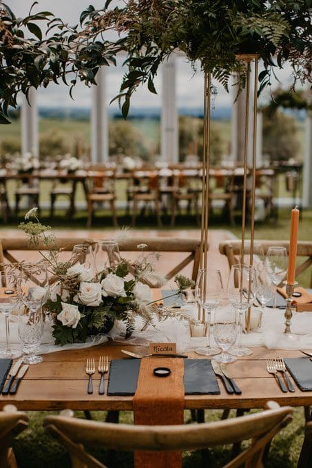 Wedding table set with rust and black cutlery, stationery and flowers