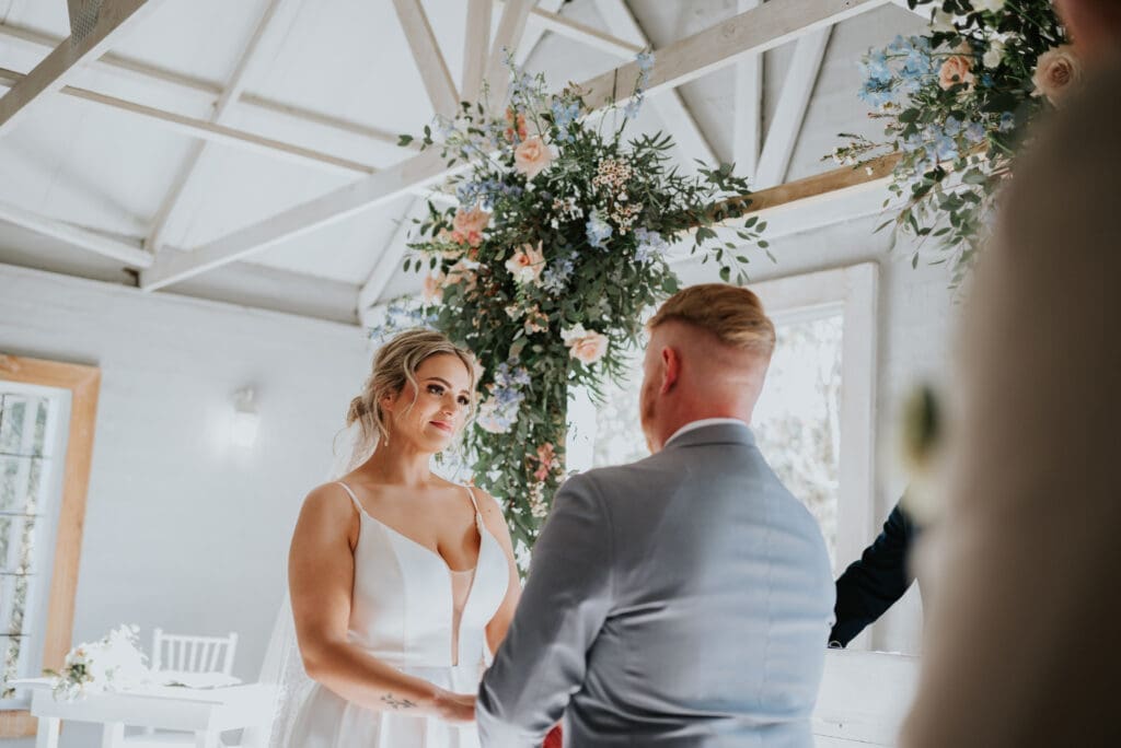 Bride and groom exchanging vows in pretty white chapel