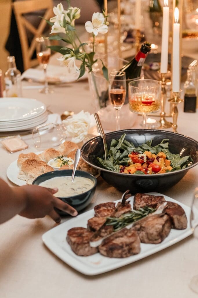 Hand placing bowls of food on candelit table