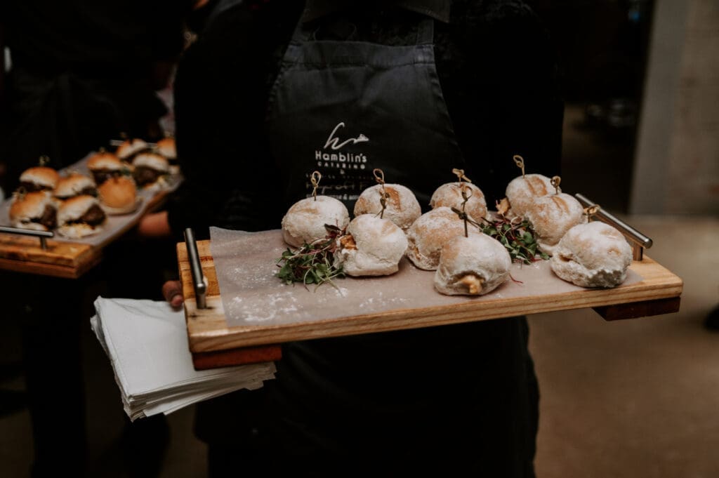 Hamblin's Catering waiter wearing back and serving pulled pork buns