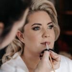 Make-up artist applying lipstick to bride
