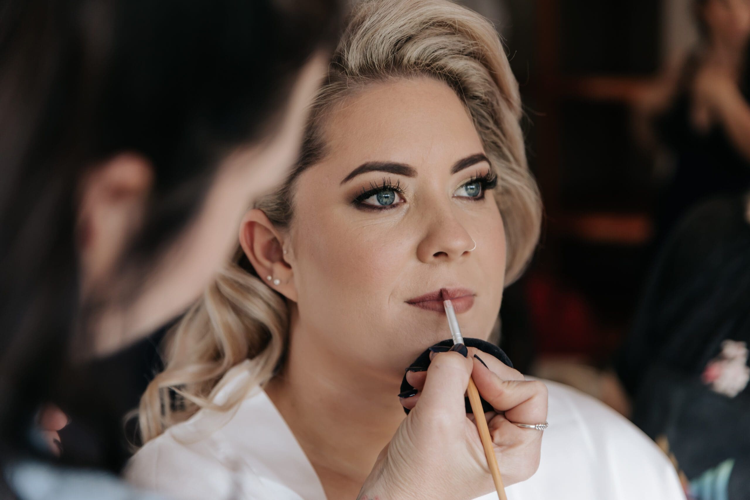 Make-up artist applying lipstick to bride