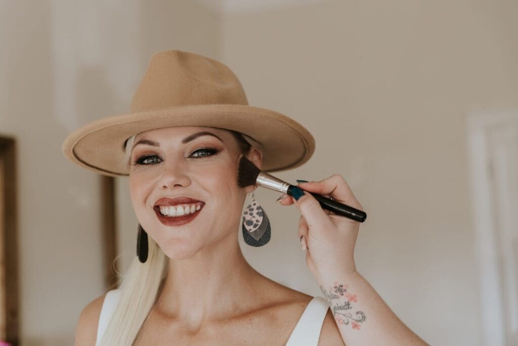 Bride in hat having her make-up done by a professional make-up artist