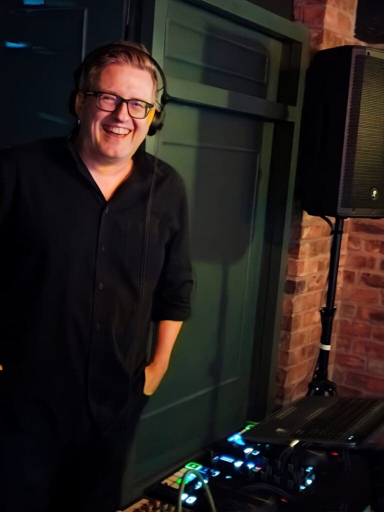 DJ Greig standing by sound equipment