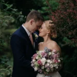 Newlyweds standing forehead to forehead in garden setting