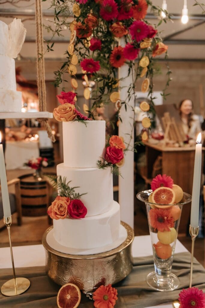 Minimalist three tier white wedding cake decorated with bright flowers