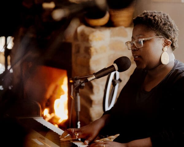 Female singer playing keyboard and singing into microphone