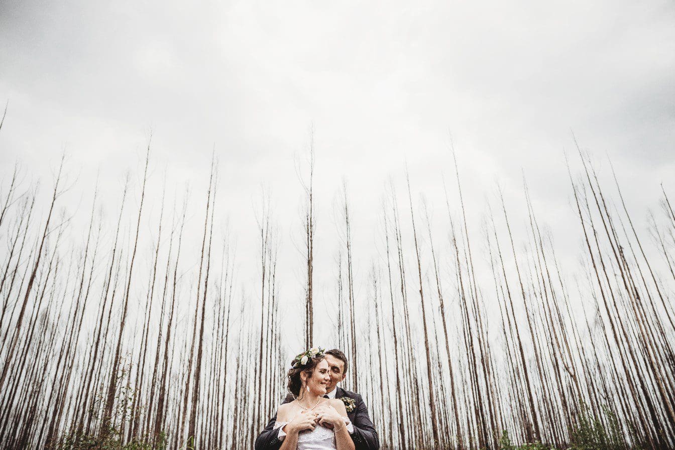Cute couple snuggling against Winter forest backdrop
