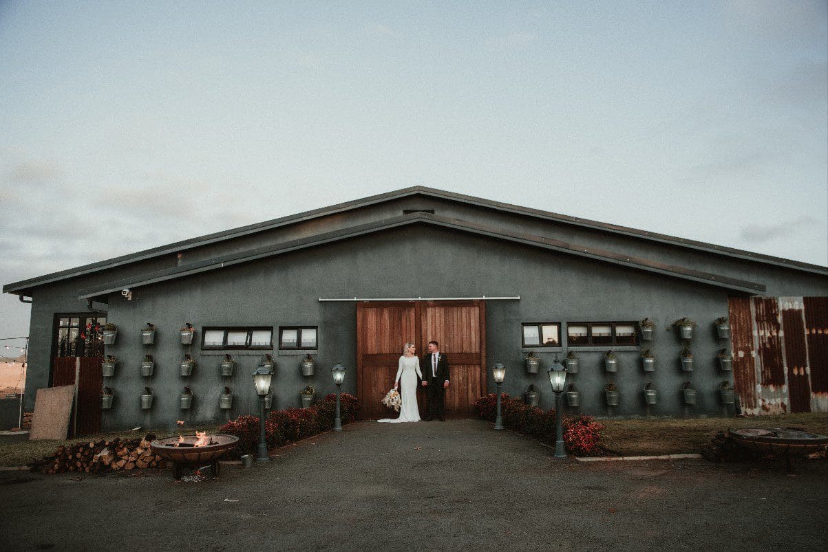 Couple holding hands with rustic shed backdrop