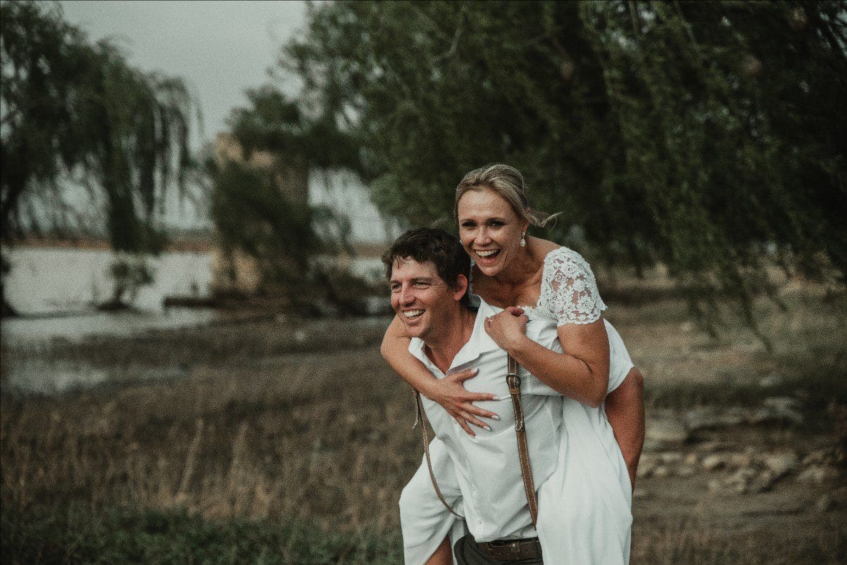 Couple laughing as groom piggybacks bride