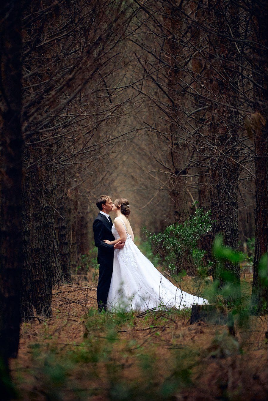 Wedding couples stealing kisses in a forest