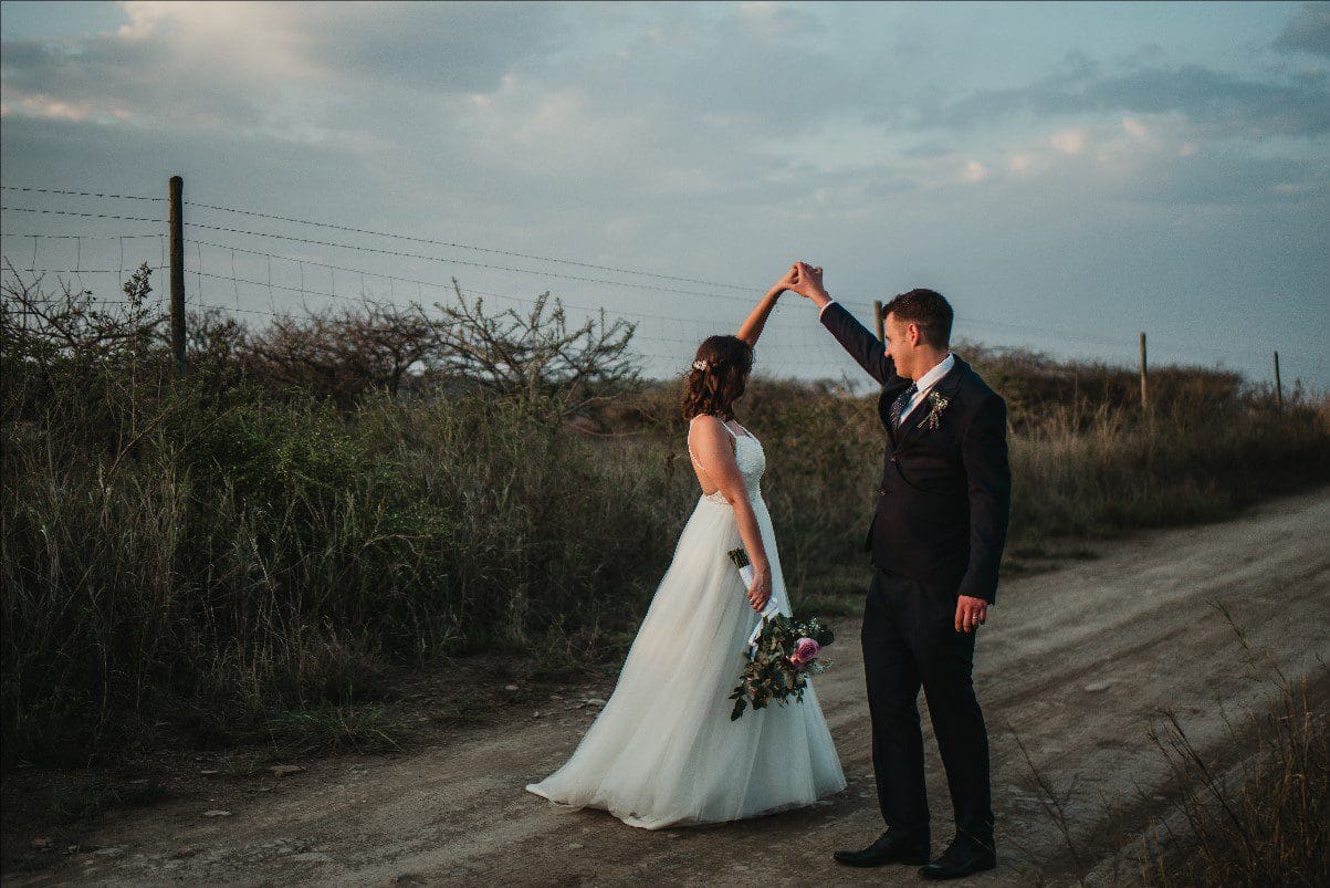 Groom twirling his bride on dirt road