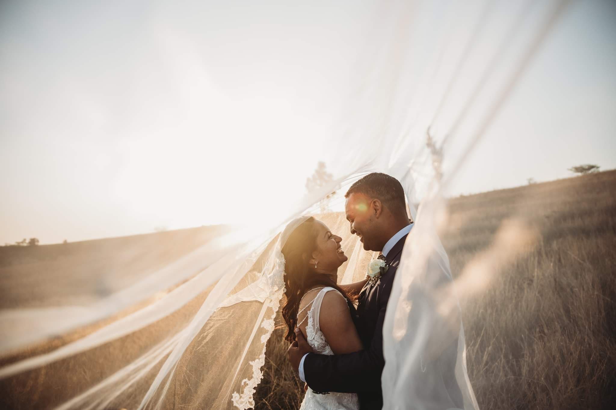 Golden hour shot of bride and groom under veil
