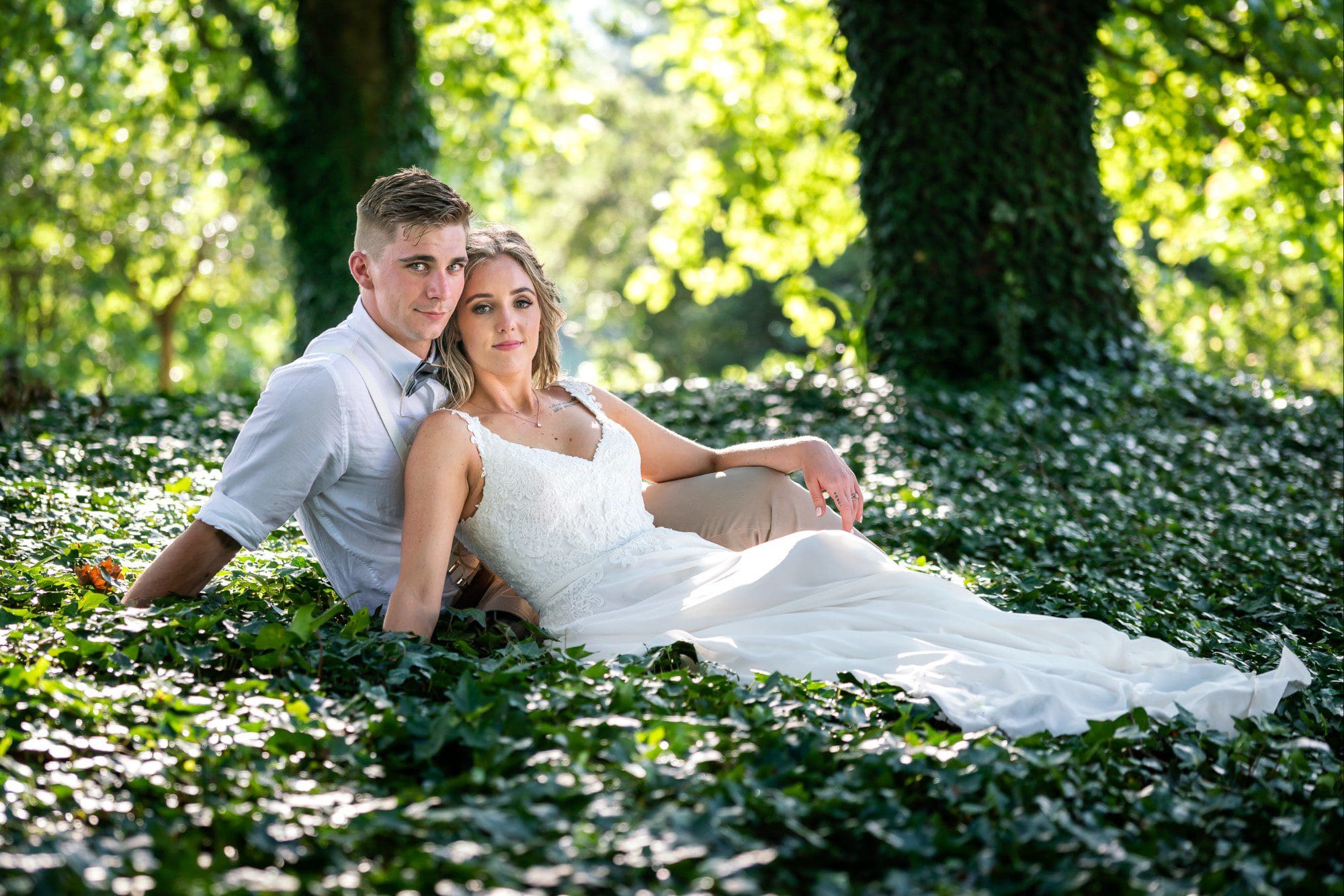 Bridal couple sitting on ground looking into camera