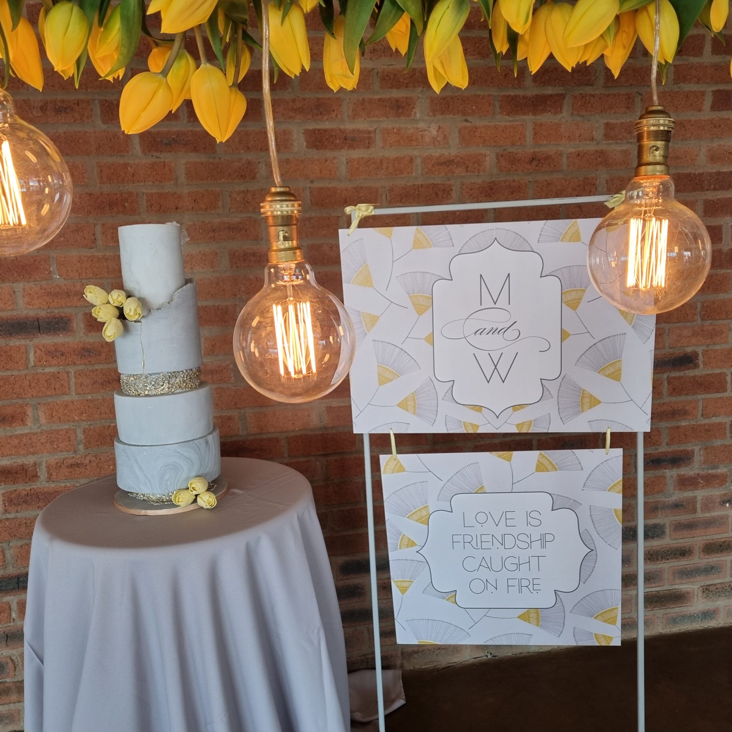 yellow and grey welcome board next to cake table