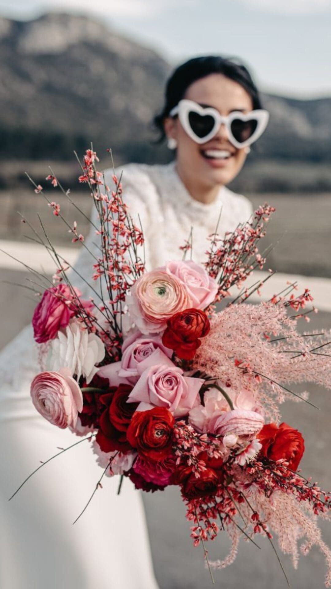 Bride in white sunglasses holding magenta bouquet