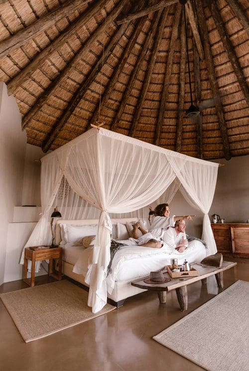 Couple viewing game from the bed in their luxury safari suite at Nambiti Plains