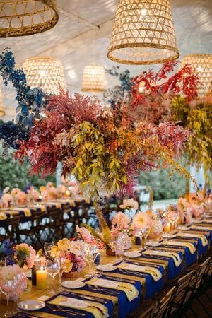 Brightly coloured flowers and grass pendant lights suspended above decorated tables suspended