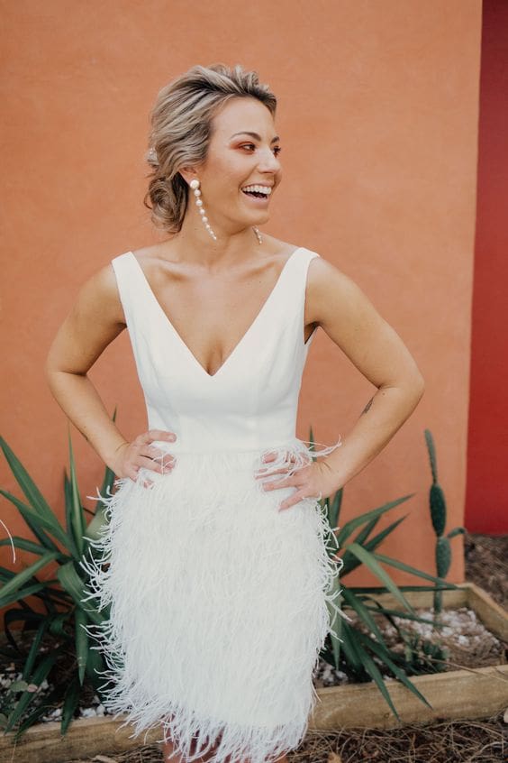 Bride wearing cute, flirty, short reception dress with feather detail