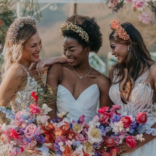 3 bride models wearing beaded head crowns and holding brightly coloured bouquets
