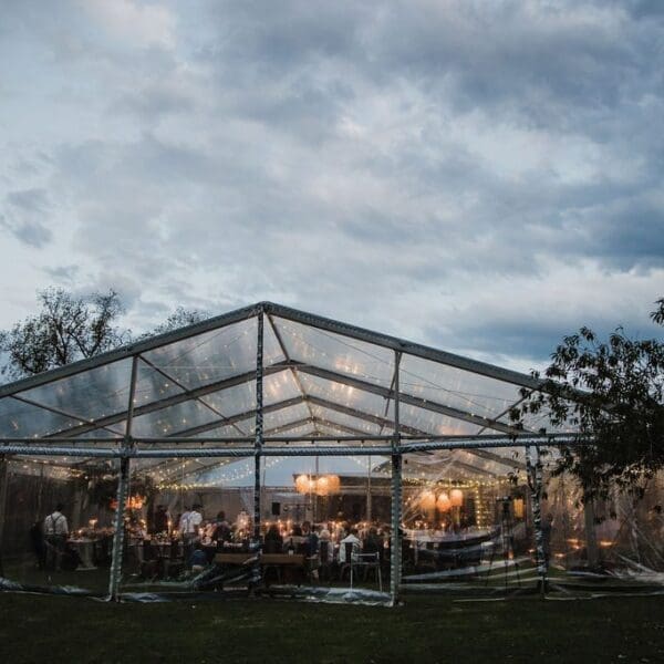 Clear marquee set up with tables and lights in the evening