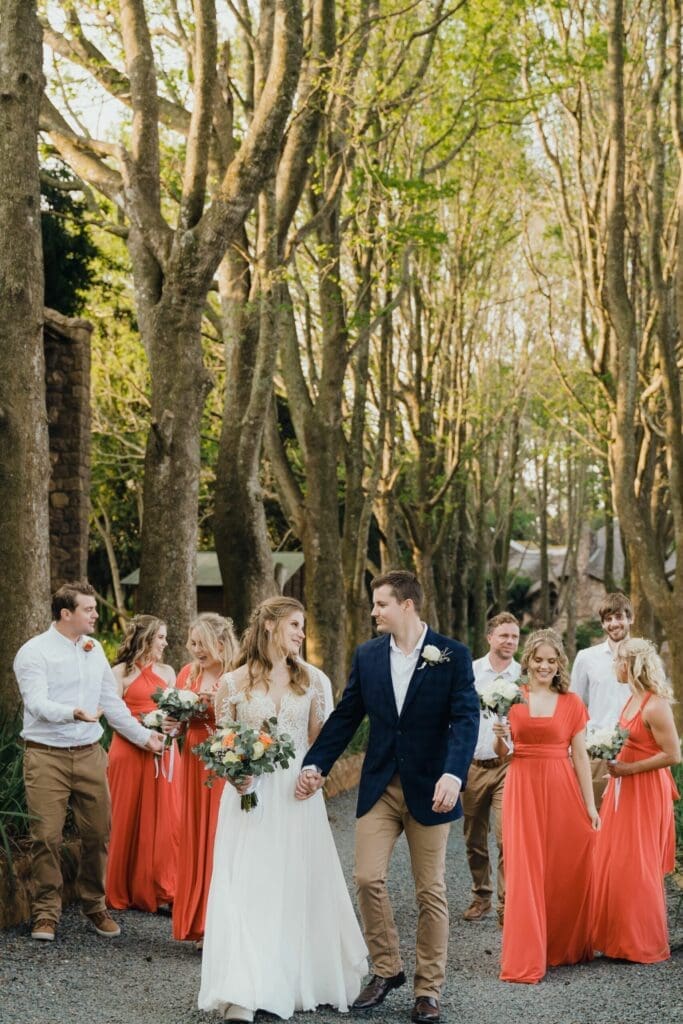 Colourful bridal party walking down tree lined avenue