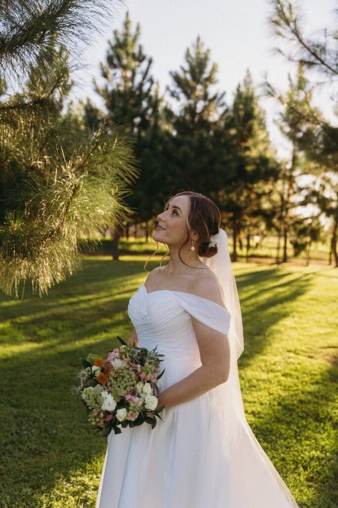 Side photo of Bride gazing upwards in lush forest field