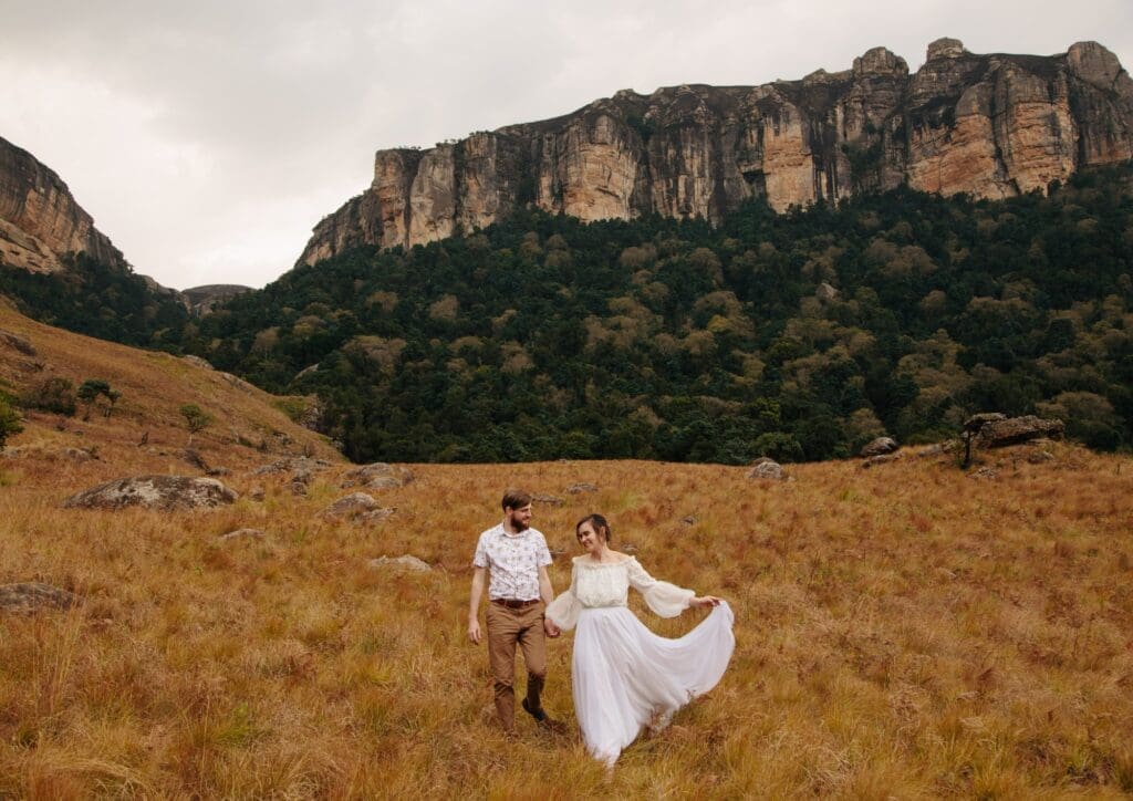 Bride and groom elopement with mountain backdrop and dried grass hill