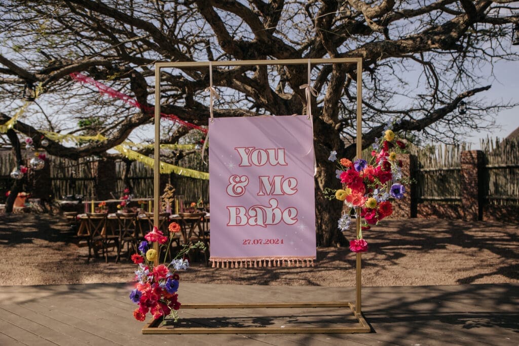 Retro wedding signage with vibrant floral swags