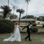 Groom leading bride across manicured lawn