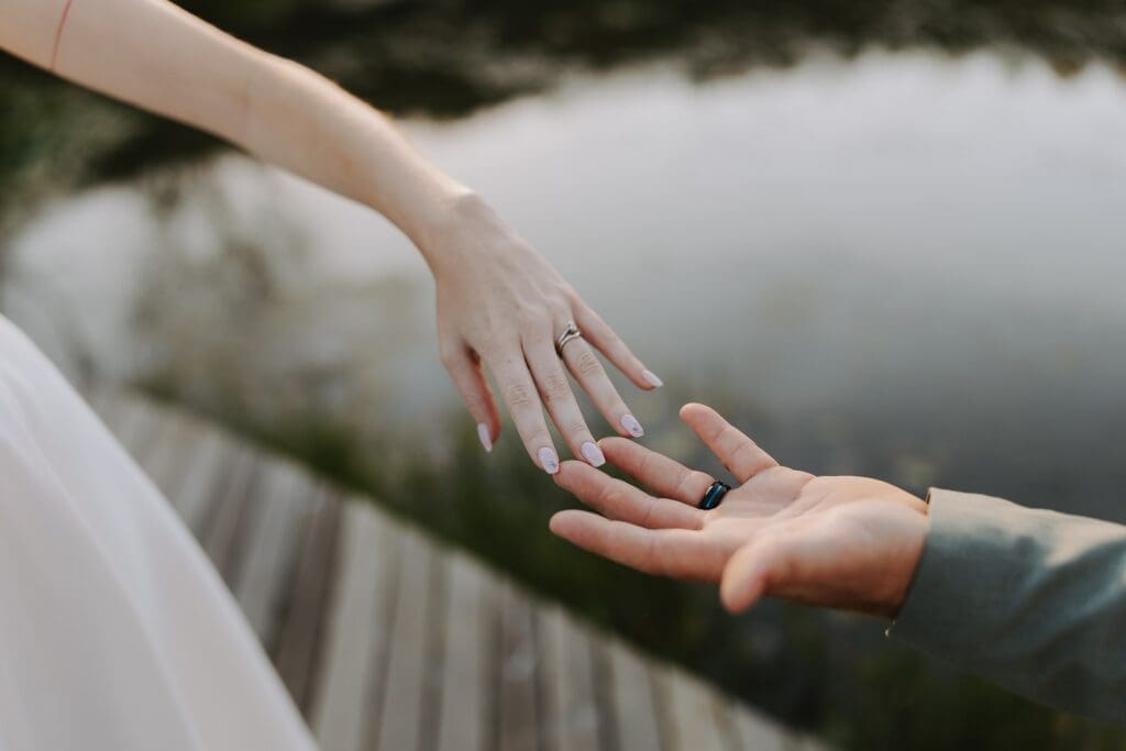 Close up of bride and grooms outstretched hands showing off wedding rings
