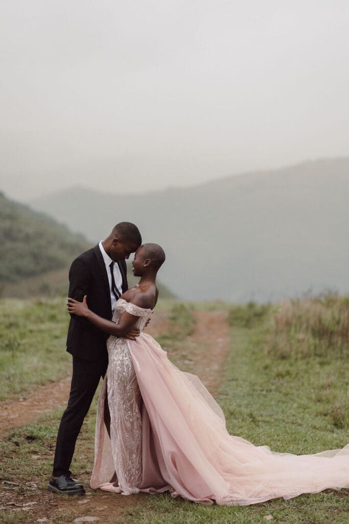 Bride and groom standing close and gazing into each others eyes with a hazy background of rolling hills.
