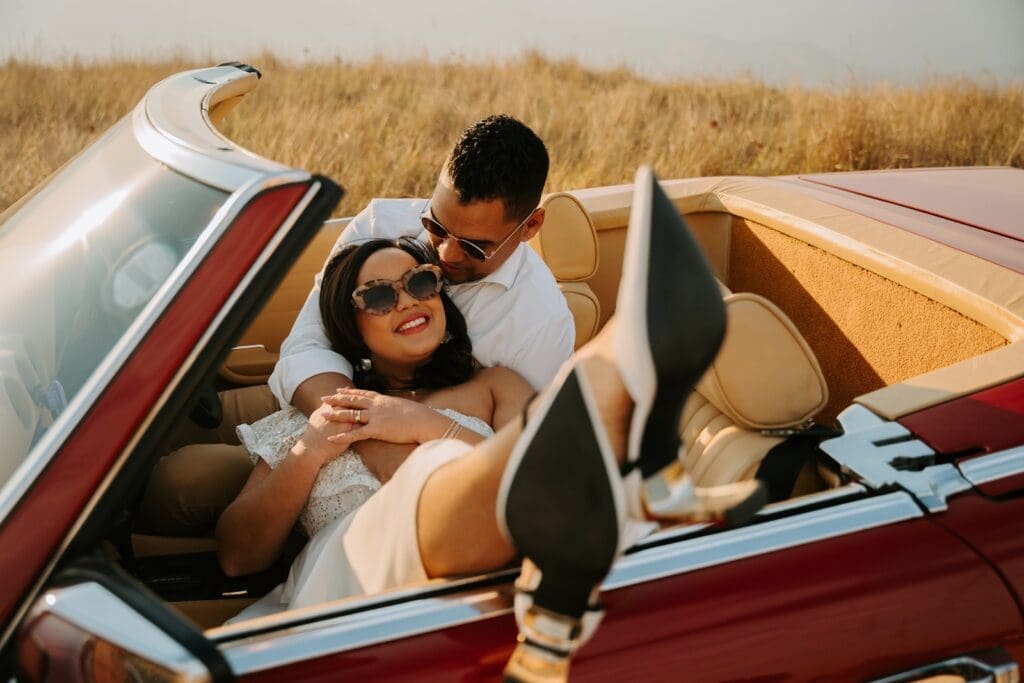 Bride and groom lounging romantically in vintage car