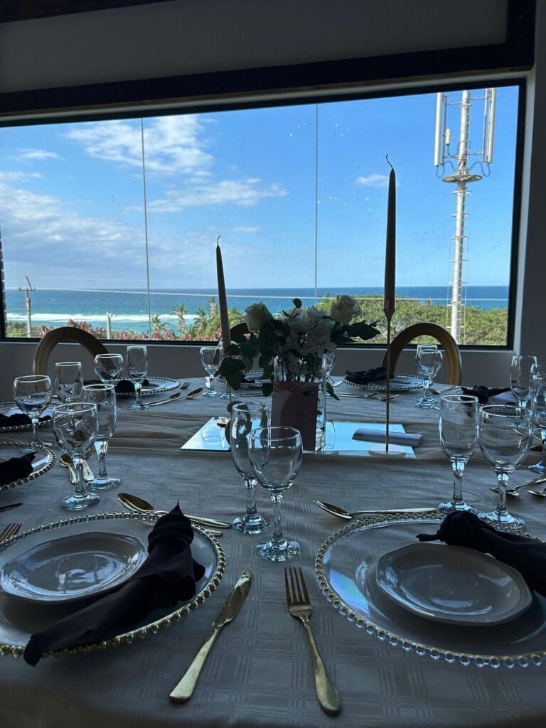 Close up view of table decor at The Lazy Moose with the ocean view behind through big glass windows