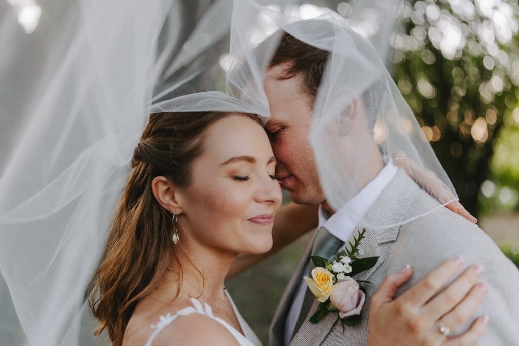 Bride and groom face close up under veil with closed eyes