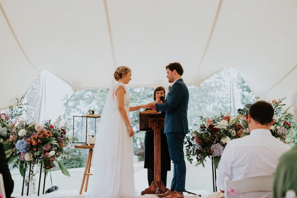 Bride and groom standing during wedding ceremony beneath stretch tent