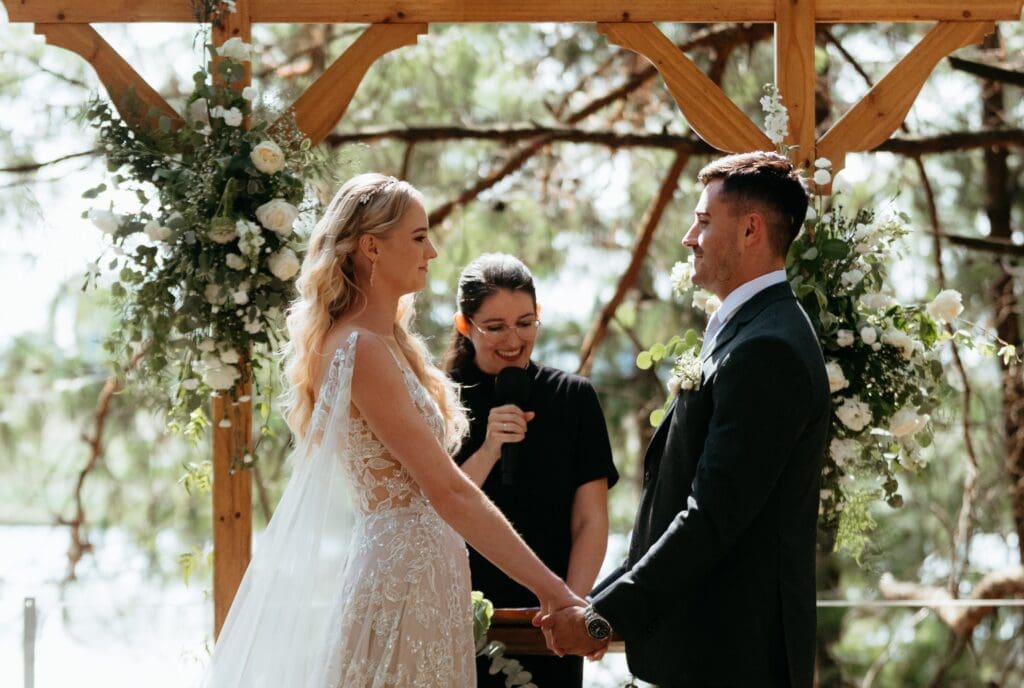 Bride and groom standing during ceremony with Rev Alice