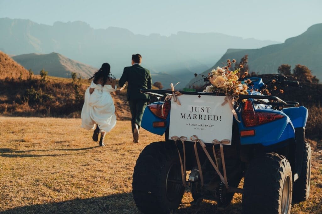 Bride and groom running hand in hand towards the mountains leaving behind their quad-bike during an elopement styled shoot.