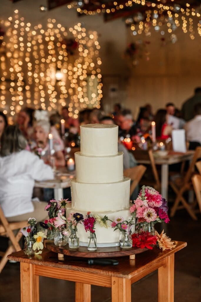Four tiered white wedding cake in reception venue at Bushwillow Park